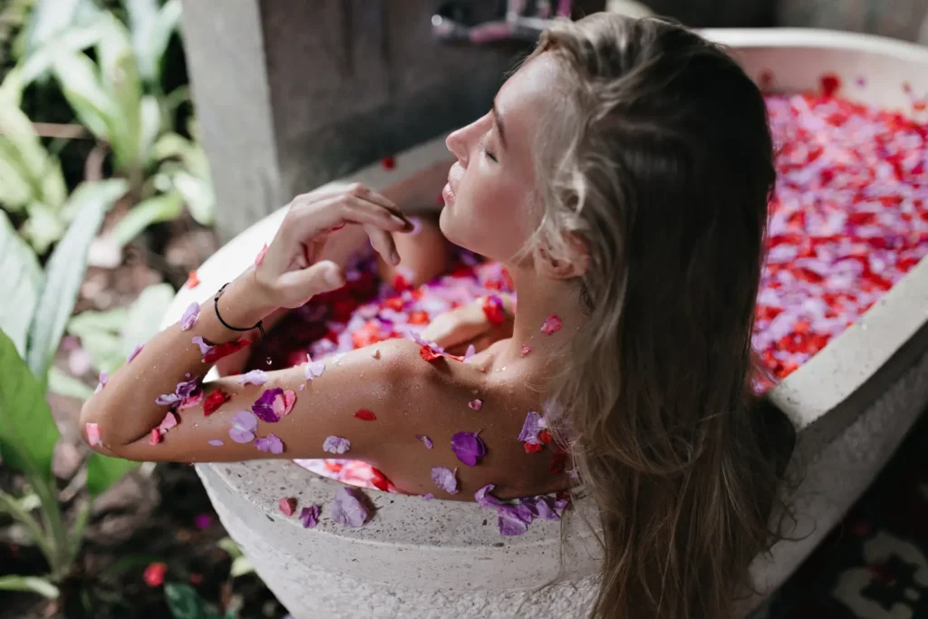 long-haired-tanned-woman-enjoying-spa-weekend-blonde-female-model-lying-bath-with-flower-petals-chilling-with-eyes-closed